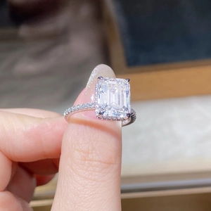 Close-up of emerald cut moissanite ring with halo setting and pavé silver band