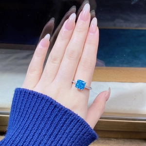 Macro shot of square-cut blue gemstone ring with pave diamonds on silver band