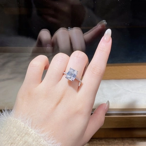 Close-up of 4-carat emerald cut moissanite ring with pavé diamond band on hand