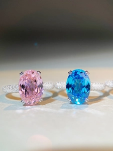 Dettaglio macro di anelli con pietre ovali rosa e blu e pavé di diamanti lucidi