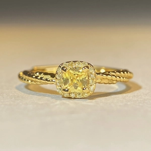 Macro shot of cushion-cut yellow gemstone ring with halo diamonds and twisted rope band