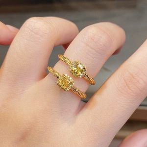 Macro detail of silver cushion cut yellow diamond rings with halo setting and twisted band