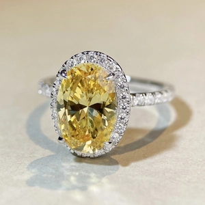 Detailed macro view of an oval yellow gemstone ring with a halo of white diamonds