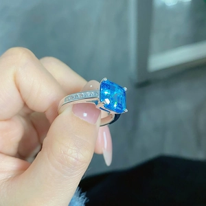 Macro shot of silver ring featuring a large square blue gemstone and pavé diamonds