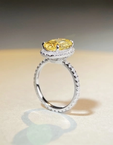Macro side view of an oval yellow gemstone ring with a diamond halo and pavé band
