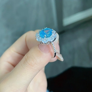 Detailed view of an oval blue gemstone ring with micro-pave setting on a silver band