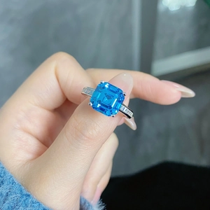 Detailed close-up of emerald-cut blue gemstone ring with baguette side diamonds