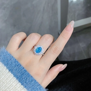 Close-up of an oval-cut blue carbon diamond ring with silver band on a hand