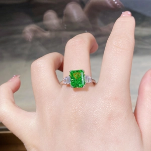 Macro detail of 925 silver ring featuring emerald cut green stone and side diamonds