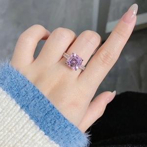 Close-up of Asscher cut pink sapphire ring with side baguettes on a finger