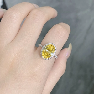Macro shot of silver ring featuring a large oval yellow stone with white diamond halo