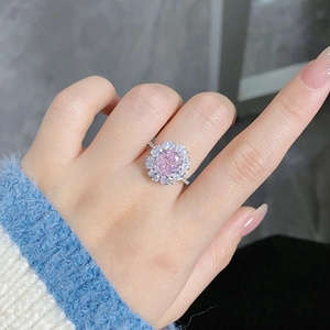 Macro view of flower cluster ring with oval pink gemstone and white cubic zirconia halo