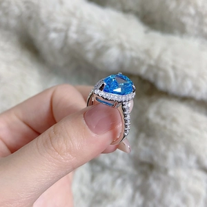 Macro shot of S925 sterling silver ring with pear-cut blue gemstone and halo accents