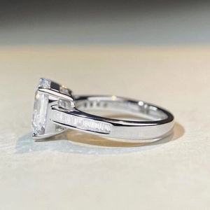 Macro shot of S925 silver ring featuring emerald cut center stone and channel set side gems
