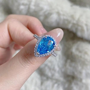 Macro detail of pear-cut blue teardrop stone ring with micro-pave diamond setting