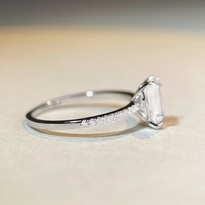 Emerald cut moissanite engagement ring with pavé side stones on a silver band