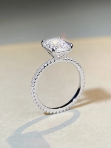 Macro shot of 4 carat emerald cut diamond ring with pavé diamonds on silver band