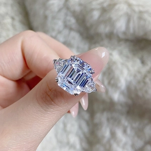 Macro view of emerald-cut sparkling gem and pear-shaped side stones on silver ring