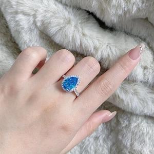 Close-up of S925 sterling silver pear cut blue sapphire halo ring on finger