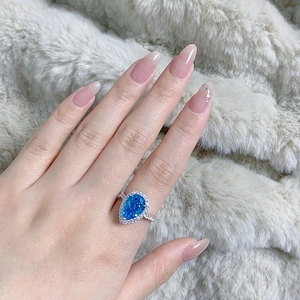 Close-up of S925 silver pear-shaped ring with blue gemstone and halo diamond setting