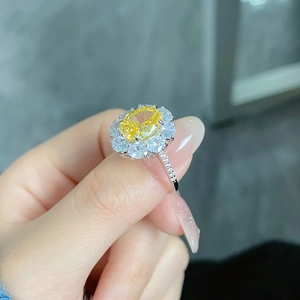 Macro shot of an oval yellow diamond flower ring with halo diamonds on a silver band