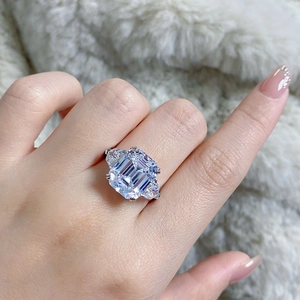 Close-up of emerald cut high carbon diamond ring with three-stone setting on hand