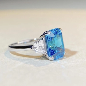 Vue macro d'une grande pierre bleue taille émeraude avec diamants latéraux sur bague argent