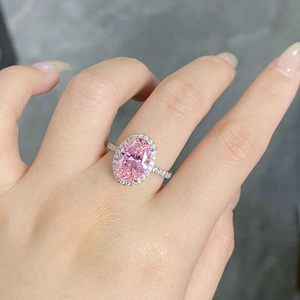 Gros plan d'une bague ovale avec pierre rose et serti de diamants sur monture argent