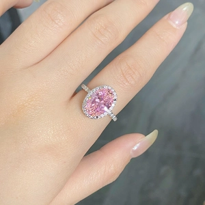 Vue macro d'une bague avec diamant rose ovale, style halo et pierres scintillantes