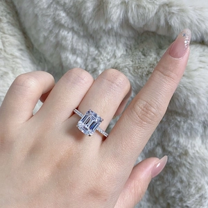 Emerald cut 4ct zircon ring on hand with four-prong setting and side accent stones
