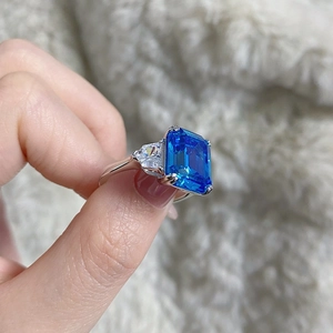 Vue macro d'une grande pierre bleue taille émeraude et diamants sur anneau argent