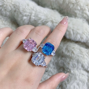 Macro shot of three emerald cut gemstone rings in pink, blue, and clear on silver bands