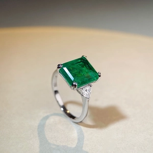 Macro shot of emerald cut green gemstone ring with pear side stones on silver band
