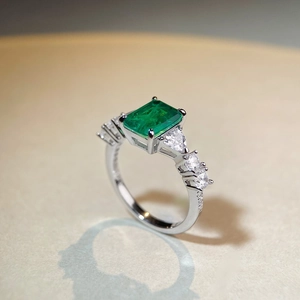 Macro shot of emerald-cut green gemstone ring with sparkling side zircons on silver band