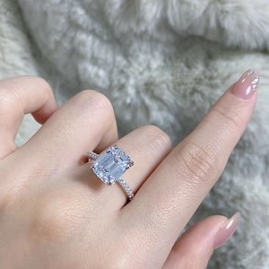 Macro shot of emerald cut 4 carat high carbon diamond ring with pavé setting on plush background