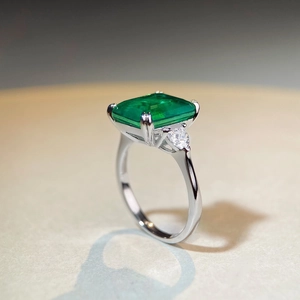 Macro shot of emerald cut green gemstone ring with side diamonds on silver band