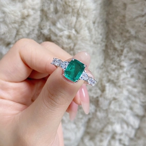 Detail of emerald cut green gemstone ring with side stones on silver band