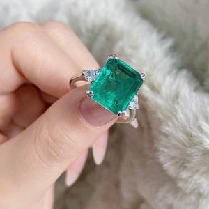 Macro shot of a three-stone S925 silver ring with a large emerald cut green gemstone