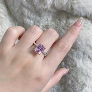 Macro shot of an emerald-cut pink sapphire ring with pavé diamond band on soft fur