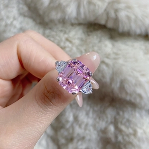 Macro detail of emerald-cut pink gemstone ring with triangular side diamonds in silver