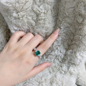 Macro view of emerald-cut green gemstone ring with side stones on silver band