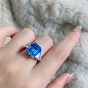 Vue détaillée d'une bague avec gemme bleue taille émeraude et diamants latéraux