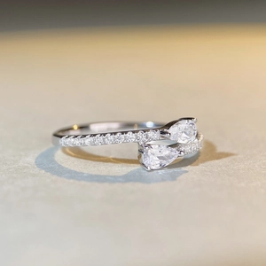 Macro shot of silver ring with dual pear-cut moissanite stones and pavé set diamonds