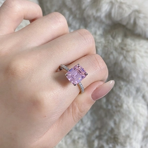 Close-up of emerald cut pink stone ring with pave diamonds on model's finger