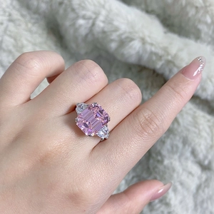 Detail of emerald cut pink gemstone ring with triangle side stones on hand