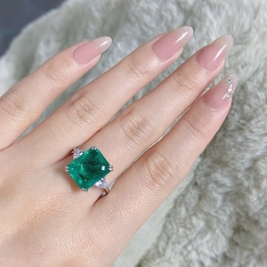 Close-up of S925 silver ring with emerald-cut green stone on a finger