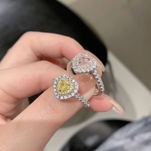 Gros plan de bagues coeur en argent avec pierres jaune et rose serties de diamants