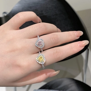 Gros plan de bagues en forme de cœur rose et jaune en argent 925 portées à la main
