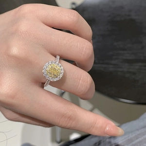 Macro detail of yellow oval halo ring with double pave diamonds on a female hand