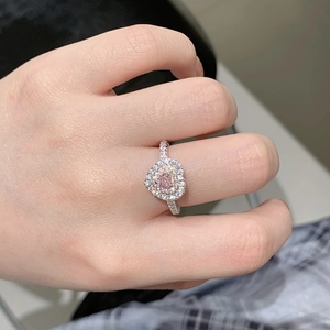 Close-up of heart-shaped pink diamond ring with double halo setting on finger